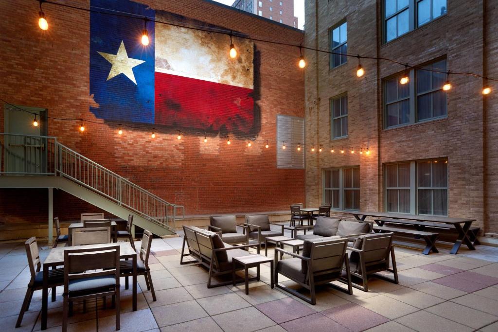 un drapeau sur le côté d'un bâtiment avec des tables et des chaises dans l'établissement Courtyard Fort Worth Downtown/Blackstone, à Fort Worth