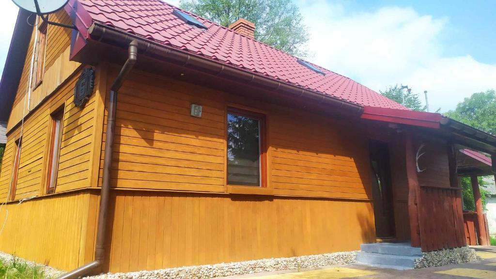una pequeña casa de madera con techo rojo en Ostoja Jarząbka 