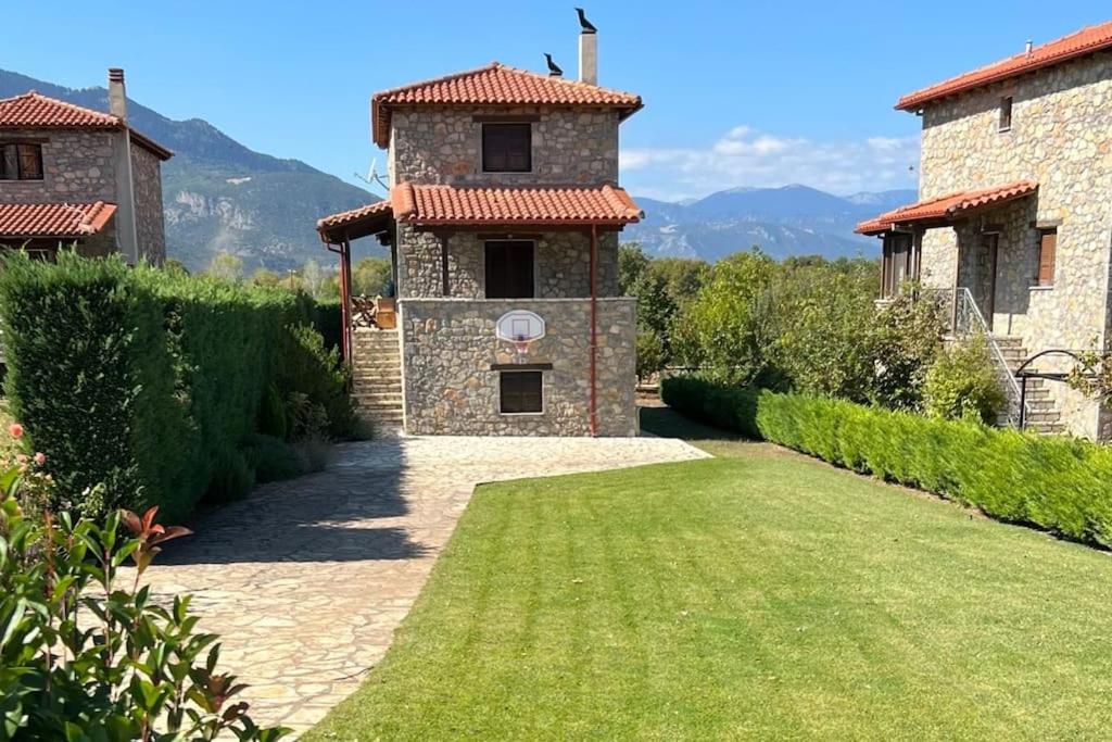 un edificio de piedra con un patio de césped delante de él en Mountain View - Full Villa, en Polydrosos