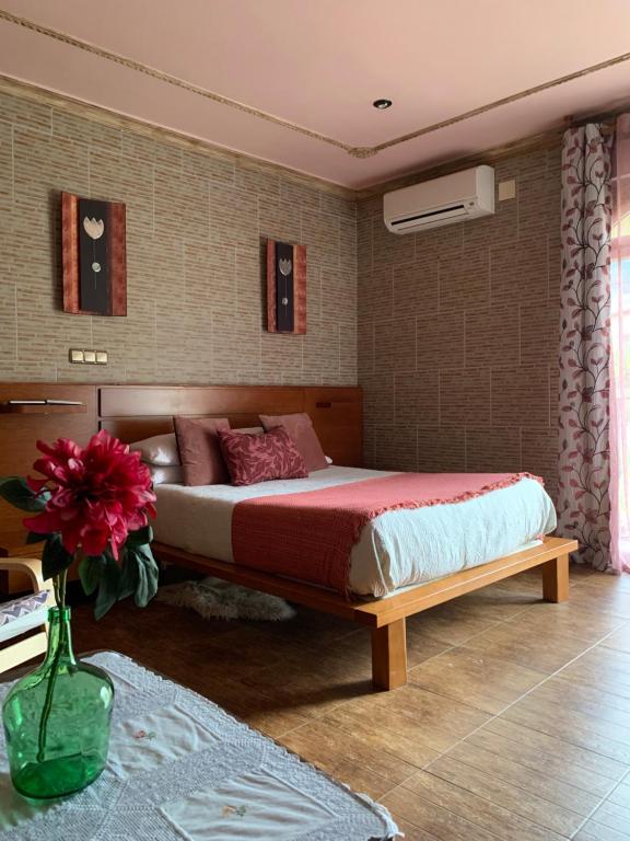 Apartamento rural FRAGARIA في Casas del Monte: غرفة نوم مع سرير كبير و مزهرية مع الزهور