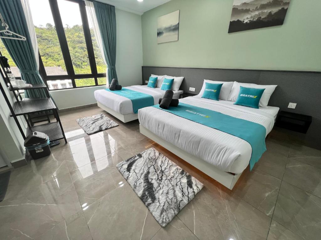 2 Betten in einem Zimmer mit 2 Fenstern in der Unterkunft BEATRIX HOTEL in Brinchang