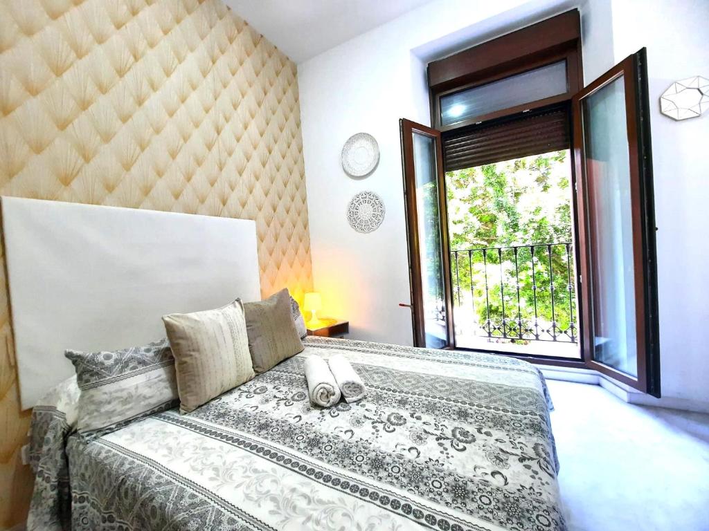 a bedroom with a bed and a large window at Budget & Lovely Rooms Las Setas in Seville