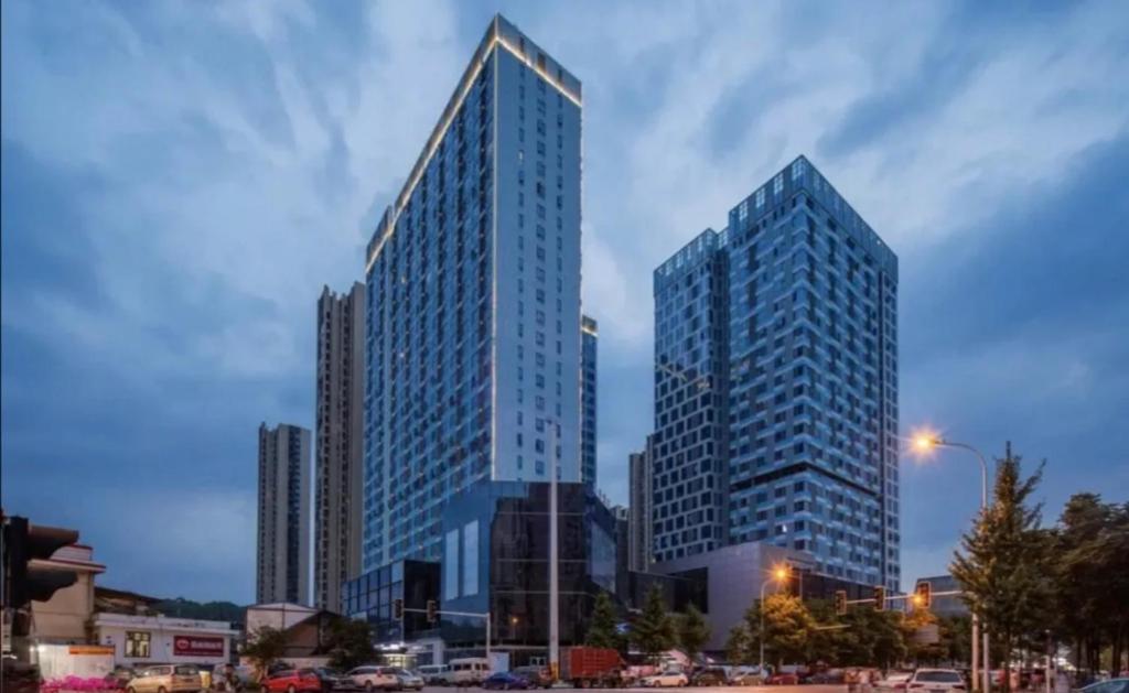 dois arranha-céus altos numa cidade ao anoitecer em Doaland Hotel, South High -speed Railway Station em Changsha
