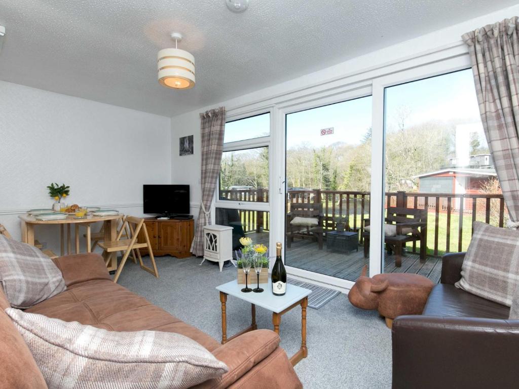 ein Wohnzimmer mit einem Sofa und einem Tisch in der Unterkunft Pass the Keys Comfortable 2 Bed Riverside Chalet near Snowdonia in Caernarfon