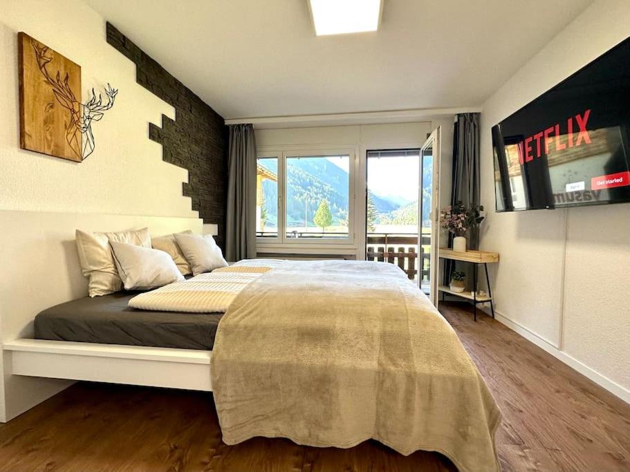 a bedroom with a large bed with a large window at Cozy place for 2 near Zermatt in Täsch