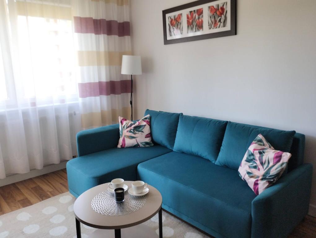 a living room with a blue couch and a table at Apartament Gardena Olsztyn Jaroty in Olsztyn