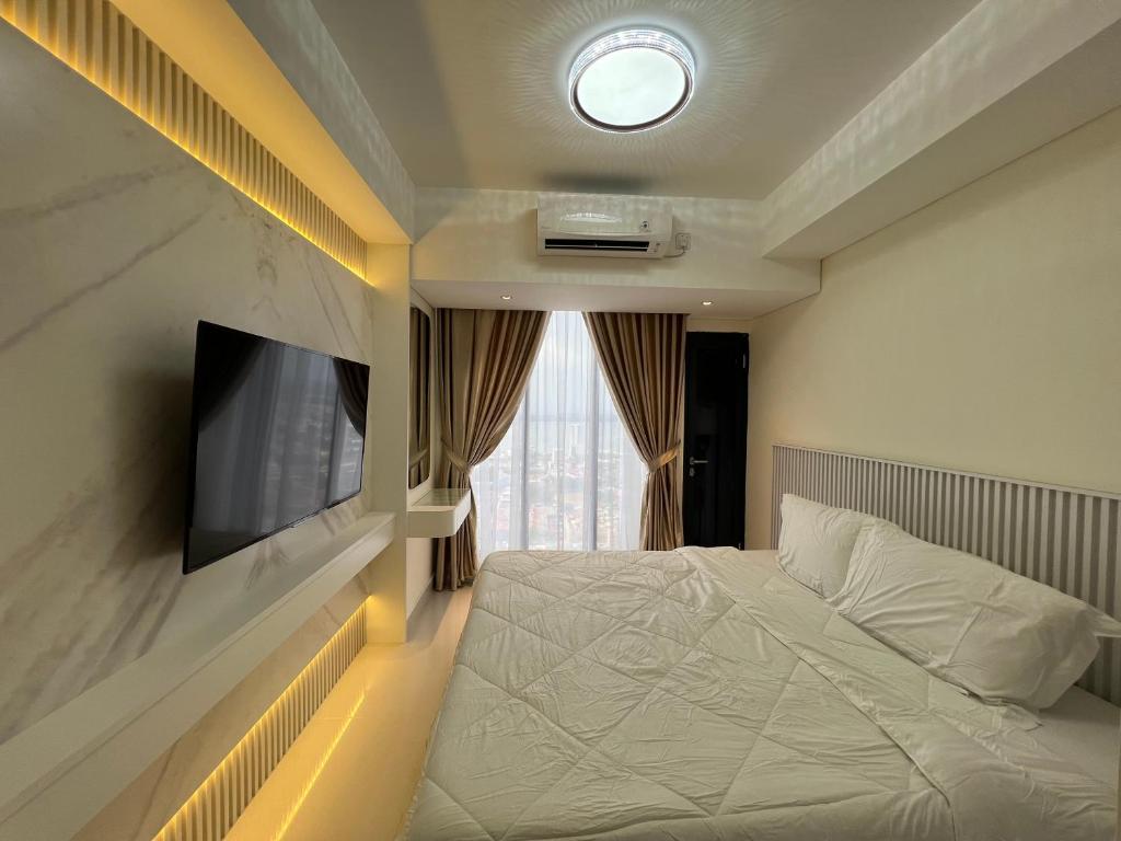 een slaapkamer met een bed en een tv aan de muur bij Pollux Habibie Studio Batam 53F (Seaview) in Batam Center