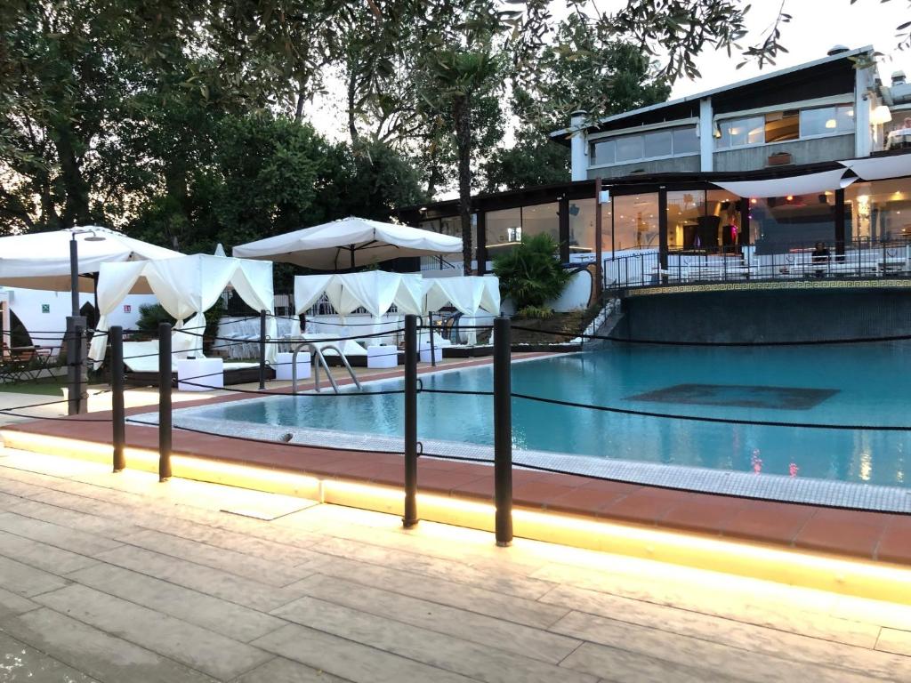 una piscina con sombrillas y mesas y un edificio en Appartamenti Montefelice, en Bardolino