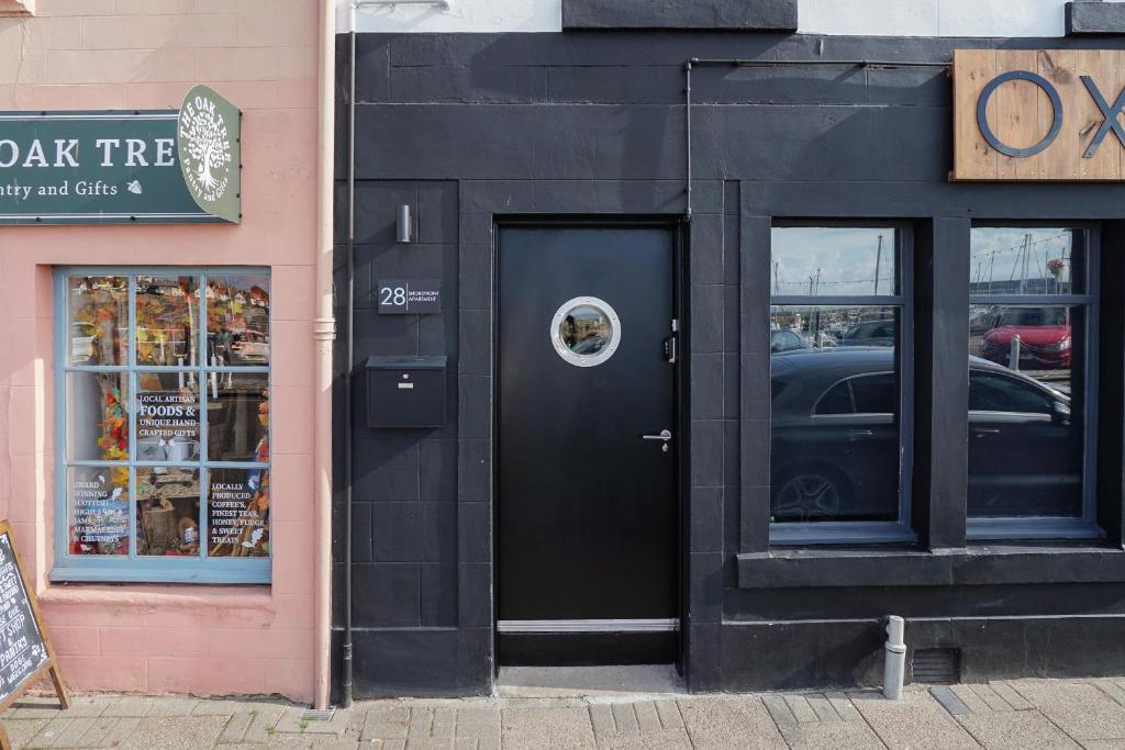 a black building with a door with a dog on it at Shorefront Apartment - Sea View with 3 Bedrooms in Anstruther