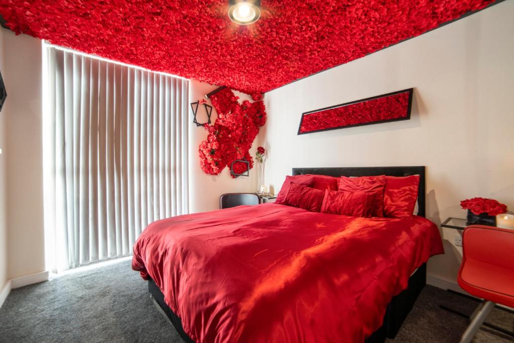 een rode slaapkamer met een groot bed met rode kussens bij Cocooning Romance in Leicester in Leicester