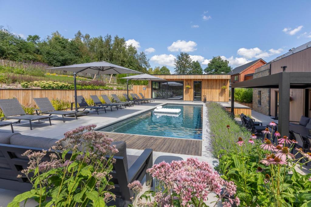 a garden with a swimming pool and patio furniture at Villa Wood - Gîte de prestige en Ardennes - 10 personnes - Sauna, jacuzzi, piscine et billard in Tenneville