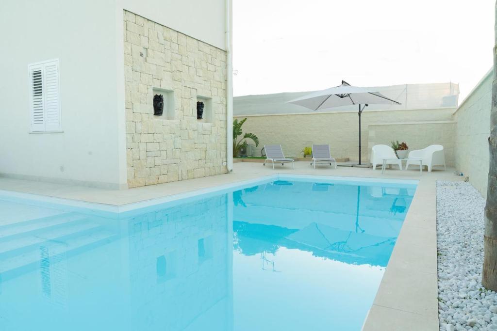 a swimming pool with blue water in a house at Vela Bianca Marzamemi in Marzamemi