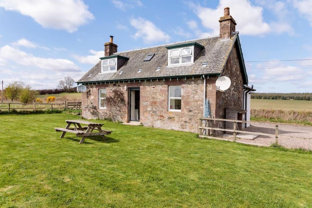 a stone house with a picnic table in front of it at Blackhill Farm Cottage in Perth