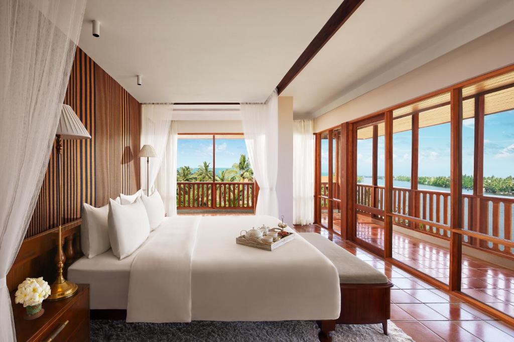 a bedroom with a large bed and a balcony at Cinnamon Bentota Beach - Signature Selection in Bentota