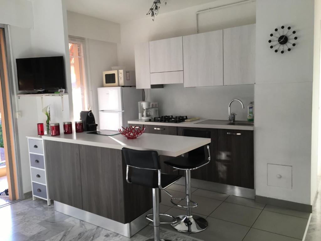 a kitchen with white cabinets and a counter with bar stools at Agréable 2 pièces à 150 m de la mer in Cagnes-sur-Mer