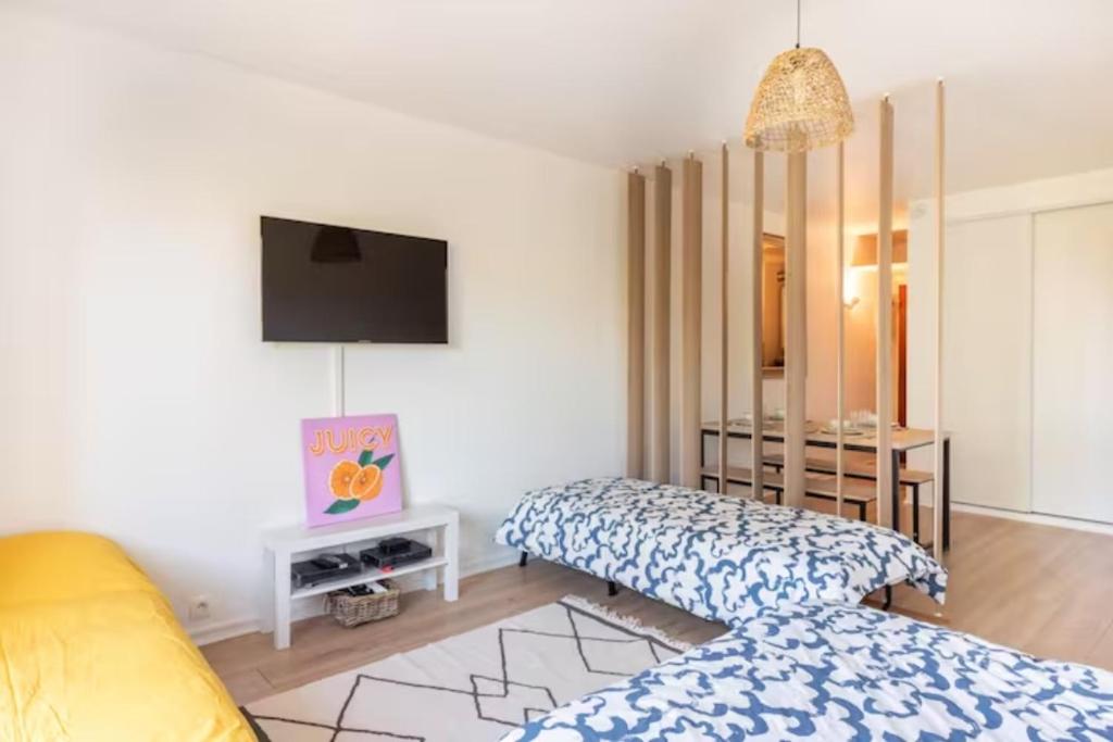 Un dormitorio con una cama y un televisor en una habitación. en Idéal familles ou pros studio 4 pers à Talence, proche tram et Bordeaux centre, en Talence