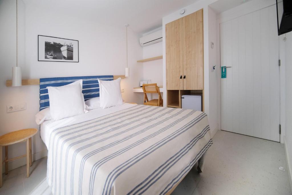 a bedroom with a large bed with a blue and white striped blanket at HOTEL BINI in Porto Cristo