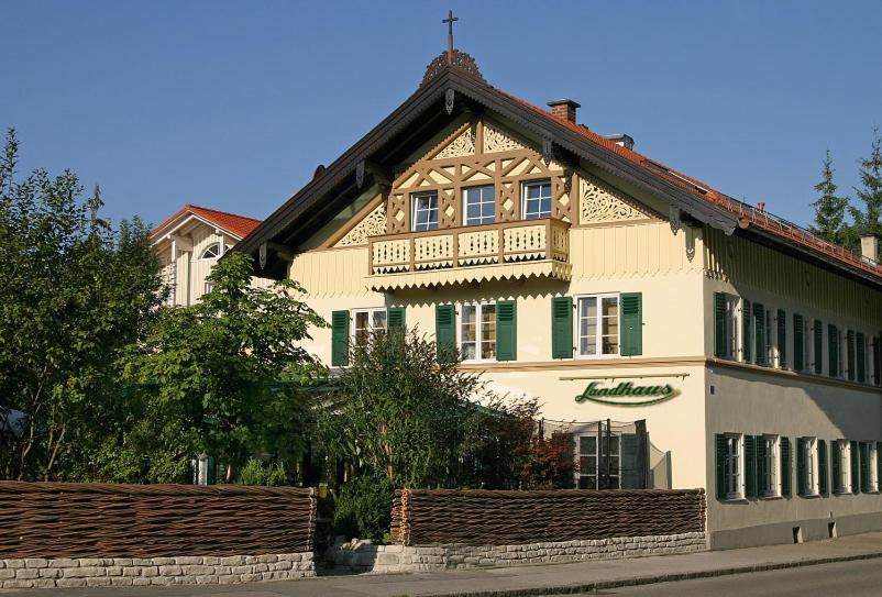 uma casa grande com uma varanda em cima em Landhaus Café Restaurant & Hotel em Wolfratshausen