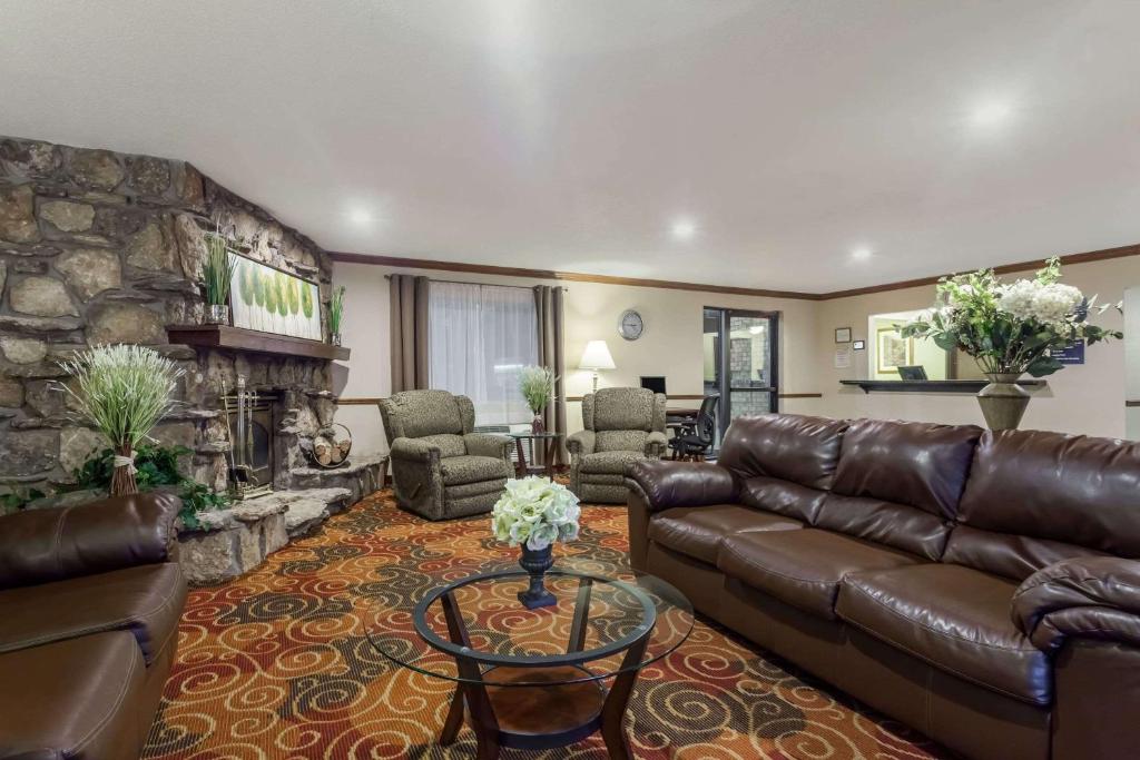 a living room with a leather couch and a stone fireplace at Days Inn & Suites by Wyndham Kaukauna WI in Kaukauna