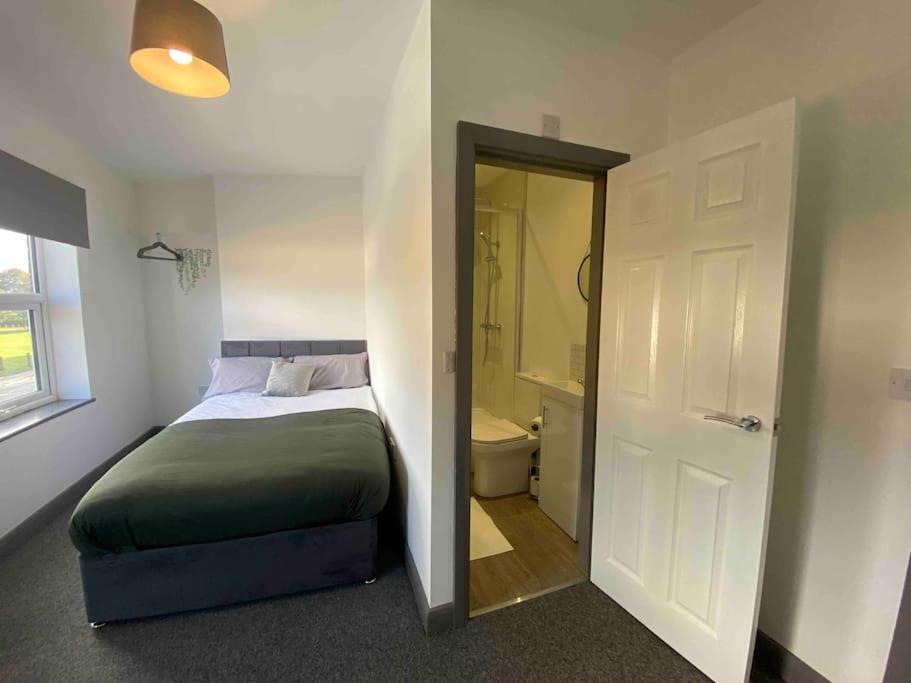 a bedroom with a bed and a bathroom with a toilet at Silver Stag Properties, Ensuite Bedrooms w Kitchen in Swadlincote