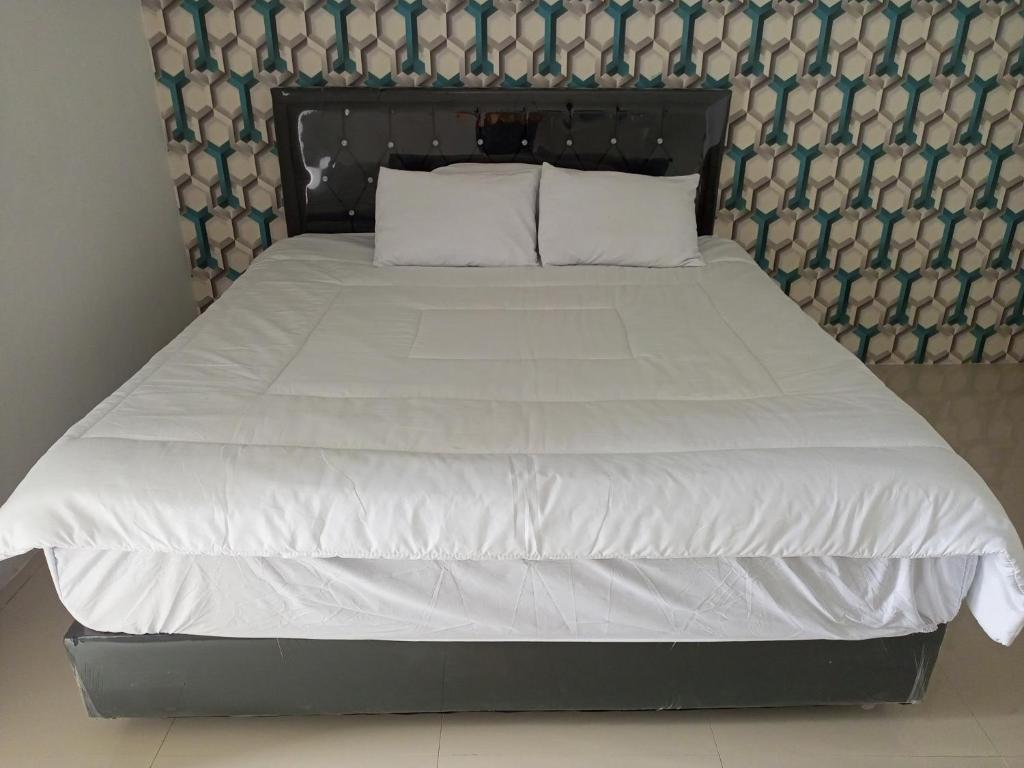 duże łóżko z białą pościelą i poduszkami w obiekcie Penginapan Lamban Queens Kamar Double Bed Lantai Bawah w mieście Kalianda
