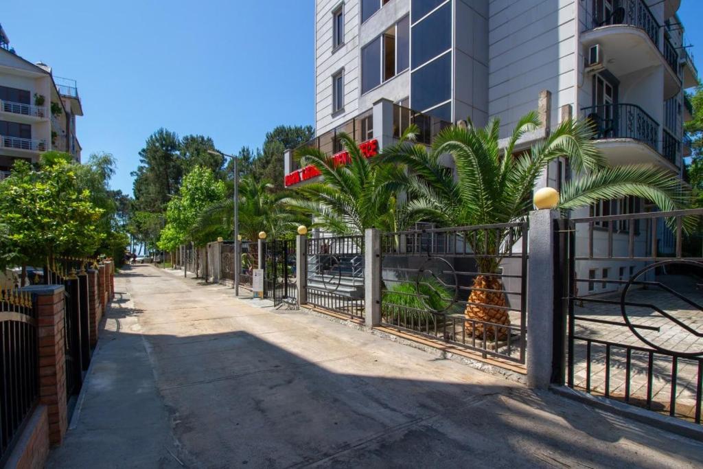 a fence with palm trees in front of a building at Golden Fleece Hotel in Ureki