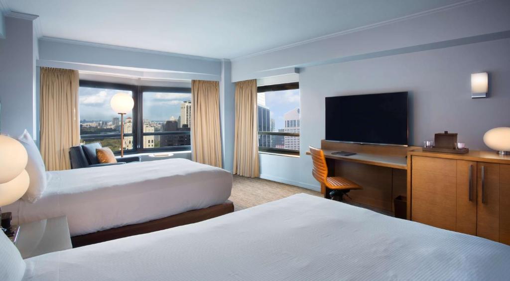 a hotel room with two beds and a desk and a television at New York Hilton Midtown in New York