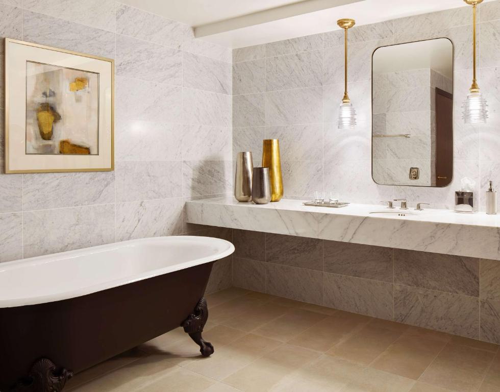 a bathroom with a tub and a sink and a mirror at New York Hilton Midtown in New York