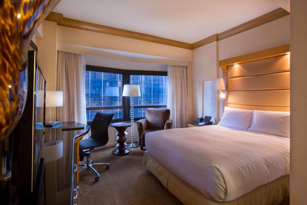 a hotel room with a bed and a desk and a window at New York Hilton Midtown in New York