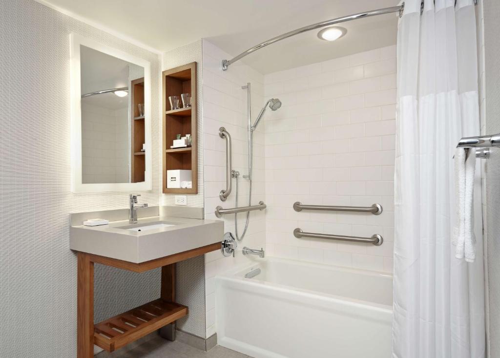a bathroom with a sink and a tub and a shower at New York Hilton Midtown in New York