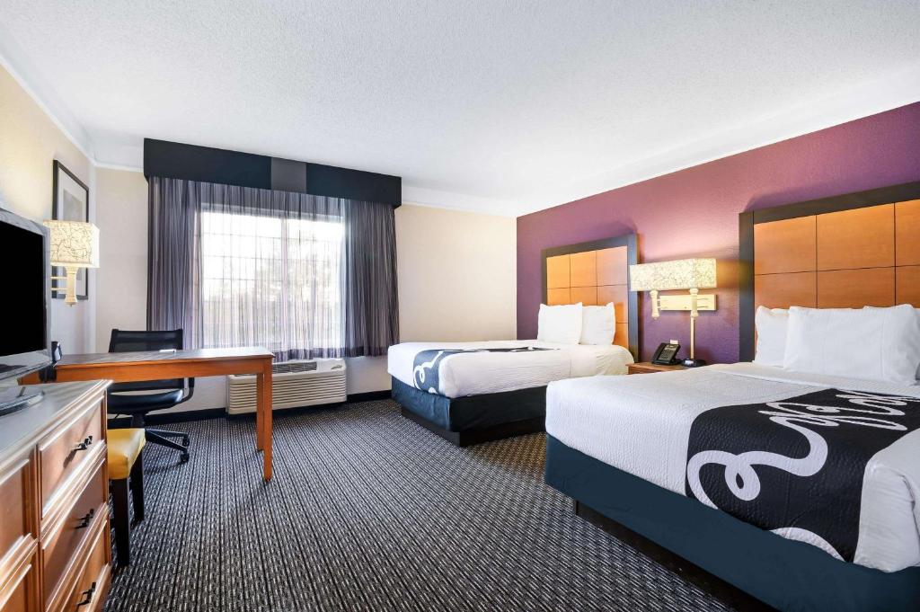 a hotel room with two beds and a desk at La Quinta by Wyndham Myrtle Beach Broadway Area in Myrtle Beach