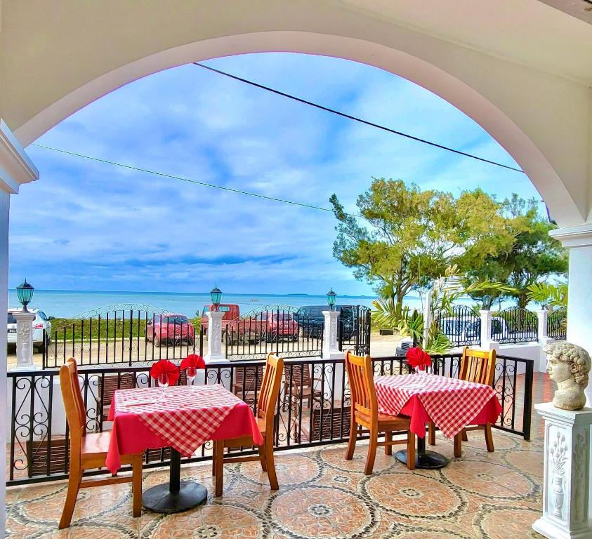 een patio met tafels en stoelen en uitzicht op de oceaan bij Little Italy Hotel in Nuku‘alofa