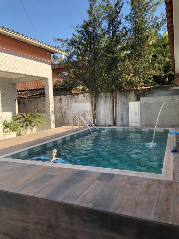 uma piscina num quintal com um deque de madeira em Casa espaçosa com Piscina e Churrasqueira 2 dorm no Guarujá