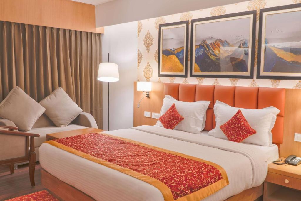 a hotel room with a large bed and a chair at Days Inn by Wyndham Gangtok Tadong in Gangtok