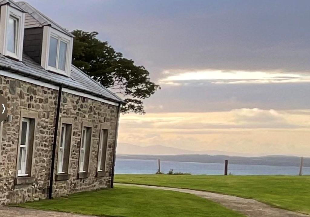 an old stone house with a pathway next to the ocean at Blaeberry Cottage in Killean