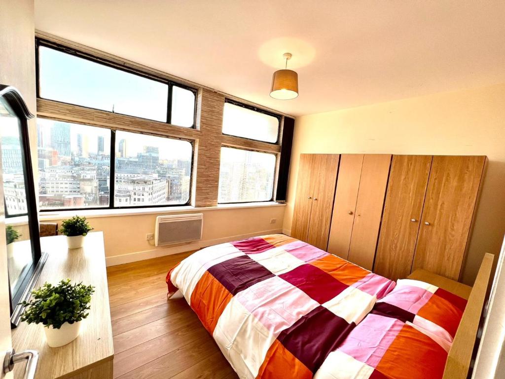 ein Schlafzimmer mit einem Bett und zwei Fenstern in der Unterkunft Two Bedroom apartment with Kitchen Facility in Manchester