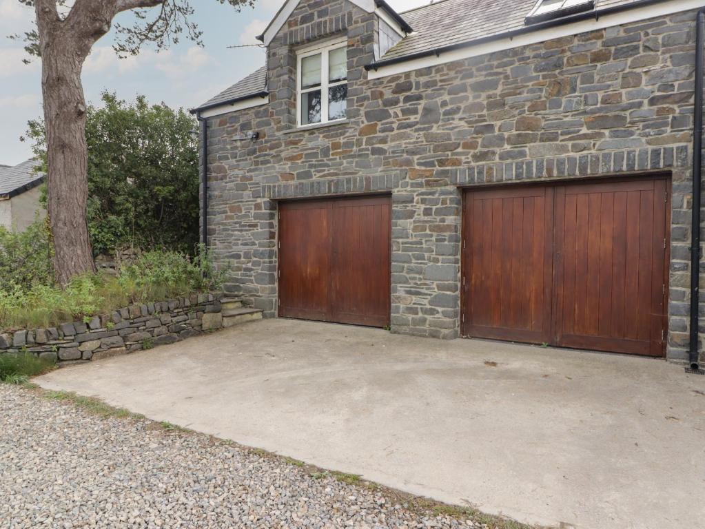 a garage with two wooden garage doors on a brick house at One Tree House in Dinas