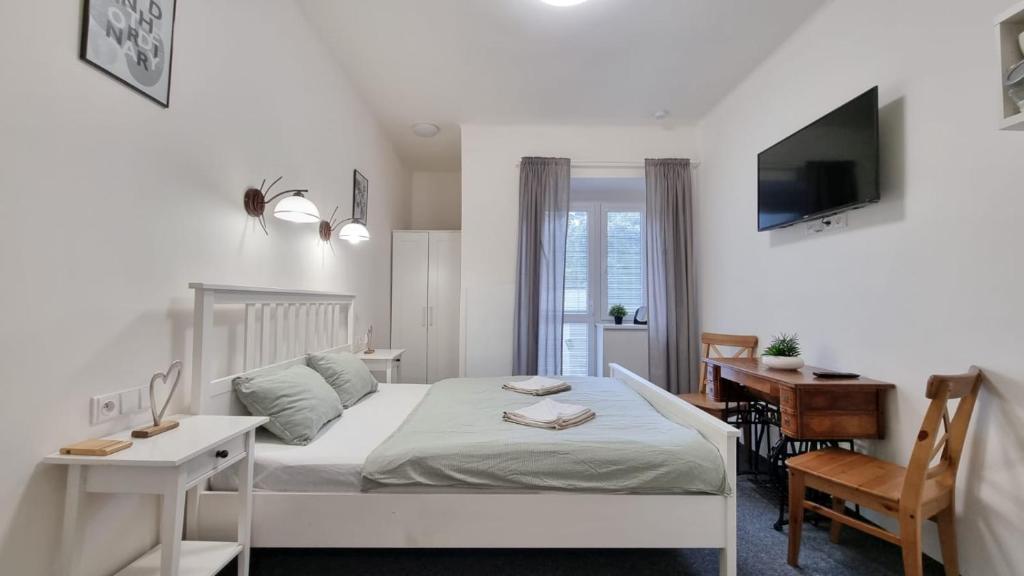 a white bedroom with a bed and a desk and a computer at Finnem Rentals Jičínská in Prague