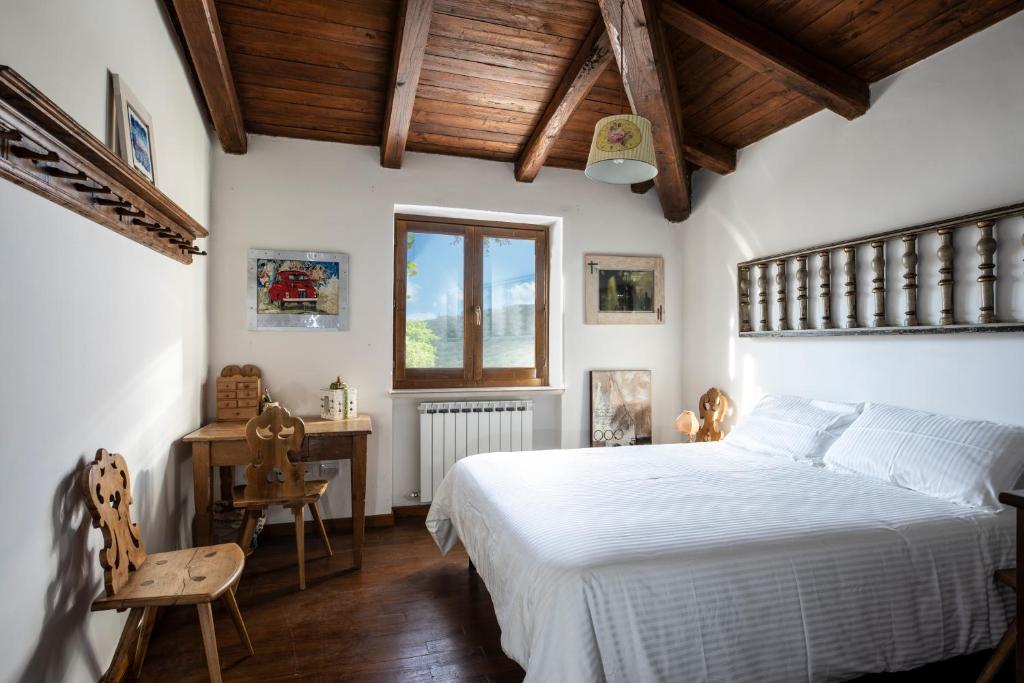 1 dormitorio con cama blanca y techo de madera en Casale Nasca, en Castelraimondo