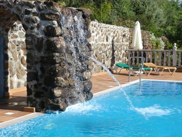a water fountain in a pool next to a stone wall at CASA COREA IV in Puntagorda