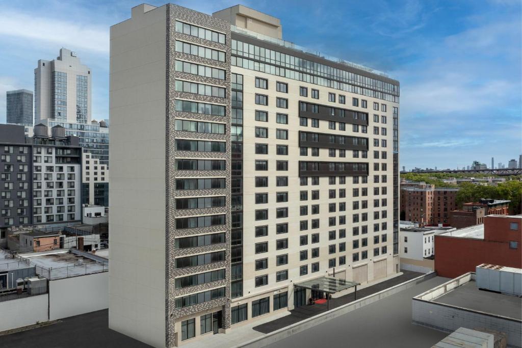 a tall white building on top of a city at Residence Inn by Marriott New York Queens in Queens