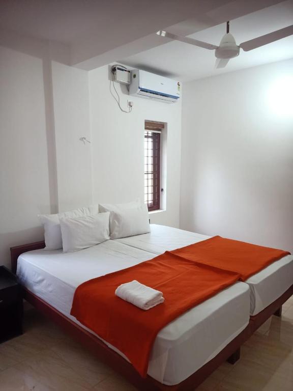 Un dormitorio con una gran cama blanca con una manta roja. en Grace Mary Residency, en Nedumbassery