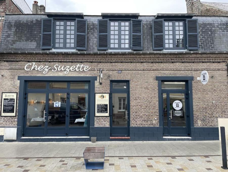 een bakstenen gebouw met een winkel met blauwe deuren bij En plein coeur du Crotoy, un pied à terre en Baie in Le Crotoy