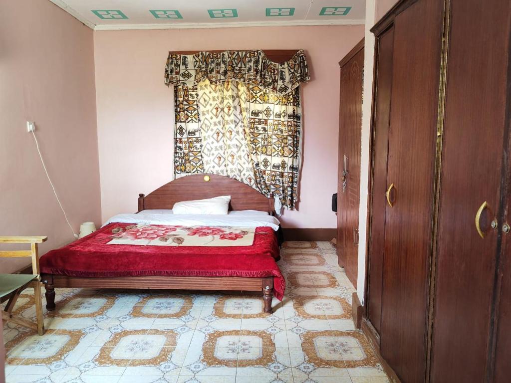 a bedroom with a bed with a red blanket and a window at Mara bush house in Sekenani
