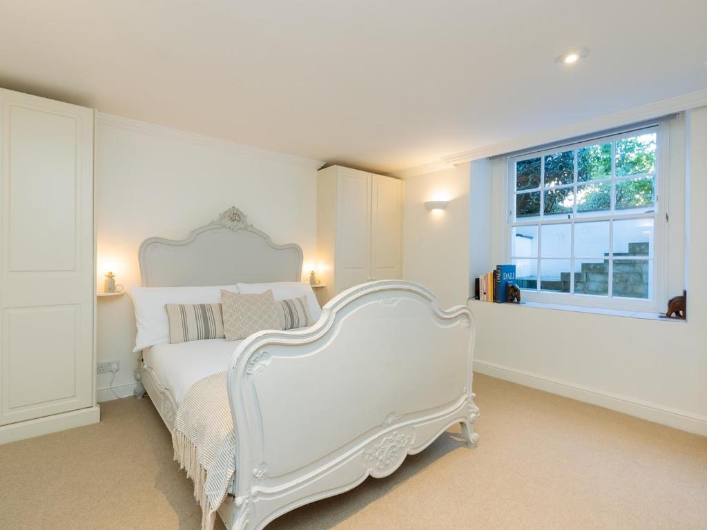 a white bedroom with a white bed and a window at Pass the Keys Stunning garden flat with parking in Bath