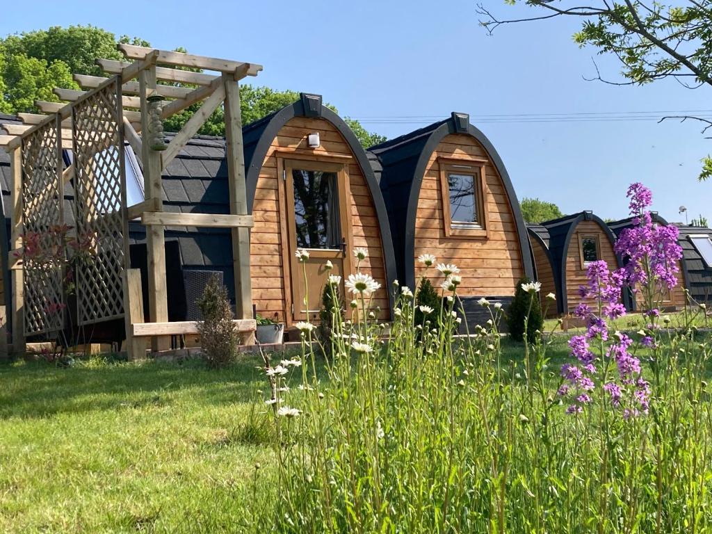 a tiny house in a field with flowers at Rabbit Glamping Pod School House Farm in Leighton