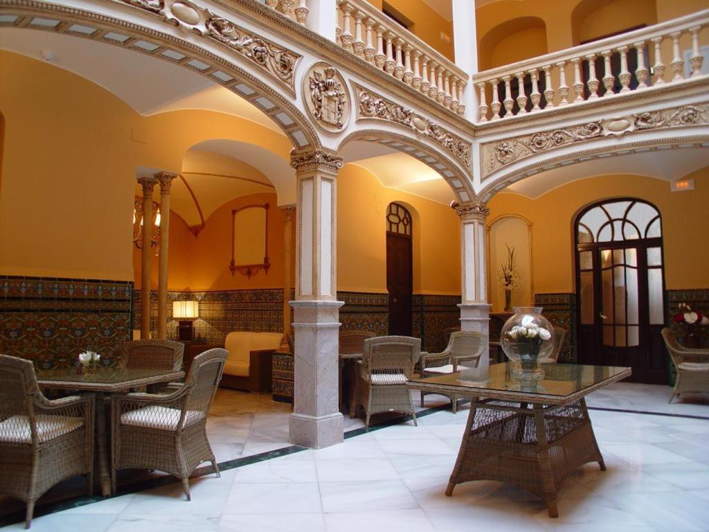 a lobby with tables and chairs in a building at Hotel Rural OLIVENZA PALACIO in Olivenza