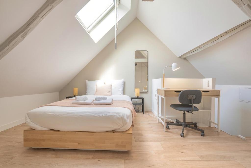 - une chambre mansardée avec un lit et un bureau dans l'établissement Triplex cosy, à Reims
