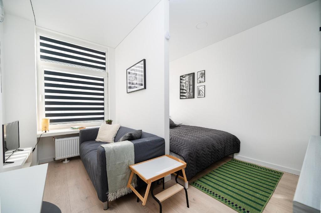 een slaapkamer met een bank, een bed en een raam bij Studios K1A in Vilnius