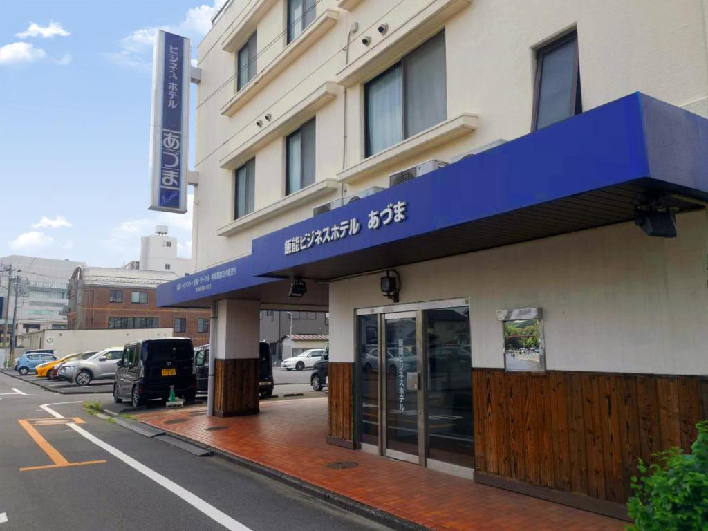 a building with a blue awning on a street at Business Hotel Azuma in Hanno